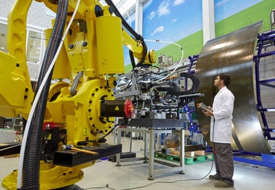 man in lab jacket operating large yellow robotic arm
